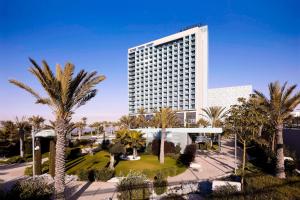 un grand bâtiment avec des palmiers devant lui dans l'établissement Le Meridien Oran Hotel, à Oran