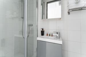 a white bathroom with a shower and a sink at L'Oasis Montparnasse in Paris +37 photos