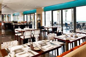 a dining room with tables and chairs and windows at Le Meridien Oran Hotel in Oran