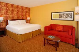 ボルチモアにあるCourtyard by Marriott Baltimore Downtown/Inner Harborのベッドと赤いソファが備わるホテルルームです。