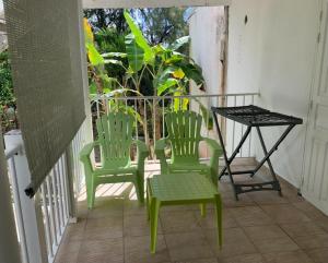 two green chairs and a table on a porch at LE JARDIN DE GABRIEL in Sainte-Anne +2 photos