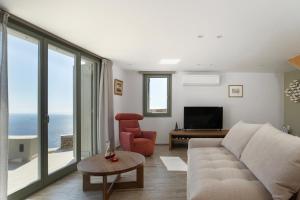 a living room with a couch and a television at Acron Andros - Luxury Villa with Private Pool in Andros