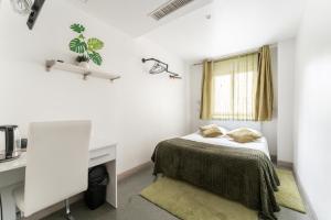 a bedroom with a bed and a desk and a window at L'Oasis Montparnasse in Paris