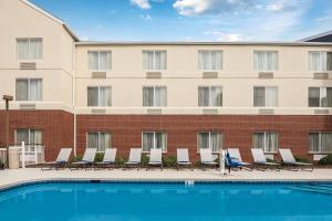 una piscina de hotel con sillas y un edificio en Fairfield Inn Charlotte Northlake en Charlotte