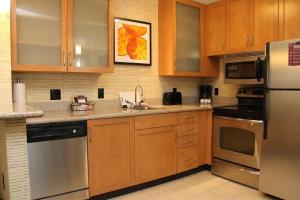 a kitchen with wooden cabinets and stainless steel appliances at Residence Inn Newport News Airport in Newport News