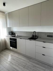 a kitchen with white cabinets and a sink at BALI apartment in central Mažeikiai SELF CHECK-IN 24H in Mažeikiai