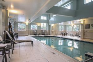 a large swimming pool in a building with tables and chairs at Residence Inn Newport News Airport in Newport News