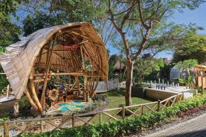 ein großes Bambusgebäude mit einem Dach in einem Park in der Unterkunft Marriott’s Bali Nusa Dua Gardens in Nusa Dua