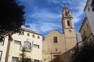 Una iglesia con una torre con un reloj. en Casa Rústica en Finestrat