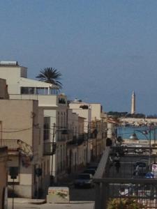 a city street with buildings and a lighthouse in the background at Seaside Apartment in San Vito lo Capo