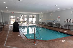 una piscina en un edificio con sillas y mesas en TownePlace Suites by Marriott Louisville Airport en Louisville