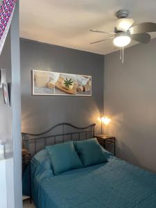 sypialnia z niebieskim łóżkiem i wentylatorem sufitowym w obiekcie Appartement proche des Thermes w mieście Balaruc-les-Bains