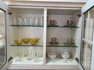 a cabinet filled with glasses and bowls on shelves at Monako Luxury Apartment in Vrnjačka Banja +8 photos