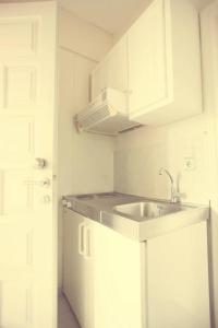 a white kitchen with a sink and a microwave at Borsalino Studios in Nydri