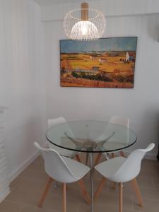 een eetkamer met een glazen tafel en 2 witte stoelen bij NEW Palacio del Sol Torremolinos in Torremolinos