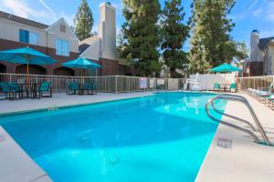 a large swimming pool with chairs and umbrellas at Residence Inn Bakersfield in Bakersfield