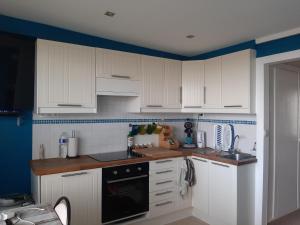 a kitchen with white cabinets and a black stove top oven at The Sweet Cocoon in De Haan