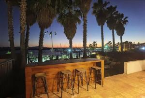 a bar with chairs and palm trees on a balcony at Playa Plateada in Ensenada