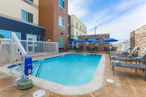 a swimming pool with chairs and umbrellas at a hotel at Fairfield Inn & Suites by Marriott Cuero in Cuero
