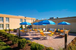 een patio met tafels en stoelen met blauwe parasols bij Fairfield Inn & Suites by Marriott Paramus in Paramus