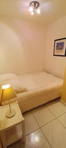 a bedroom with a bed and a table with a lamp at Ancora- Appartement vue mer et place de parking in Les Sables-dʼOlonne