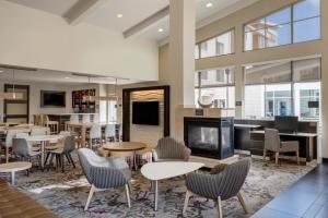 a lobby with tables and chairs and a fireplace at Residence Inn by Marriott Bloomington in Bloomington