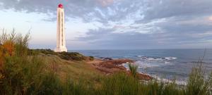 a lighthouse on the shore of a beach with the ocean at Maisonnette du Sémaphore - Jardin, piscine & parking à La Chaume in Les Sables-d'Olonne +7 photos