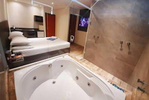 y baño con bañera grande y cama. en Motel Veleiros - Zona Norte en São Paulo