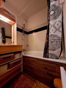 a bathroom with a bath tub with a shower curtain at appartement t2 cosy 4 à 6personnes la gentiane in Superdevoluy