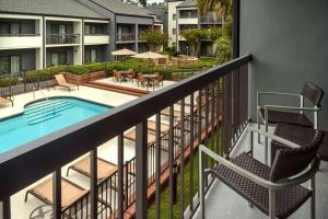 a balcony with a pool and chairs and tables at Courtyard by Marriott Tallahassee Downtown/Capital in Tallahassee