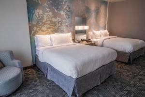 a hotel room with two beds and a chair at Courtyard by Marriott Greenville Mauldin in Greenville