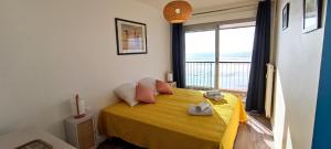 1 dormitorio con cama amarilla y vistas al océano en MIREILLE - Appartement 4 etoiles vue mer - 2 a 4 pers en Les Sables-dʼOlonne