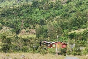 a small red house on the side of a mountain at Cabañas Piukewen in Riñinahue