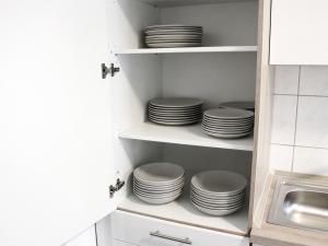 a stack of plates on shelves in a kitchen at LIGHTPLACE • Größere Gruppen • 4 Einzelzimmer • Boxspring • Smart TV • Biergarten • Restaurant in Braunschweig