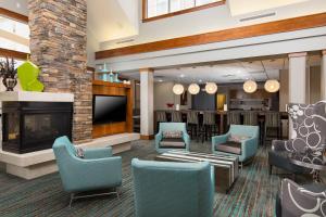a lobby with chairs and a fireplace and a bar at Residence Inn Dayton North in Dayton