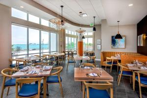 a restaurant with tables and chairs and windows at SpringHill Suites by Marriott Boston Logan Airport Revere Beach in Revere
