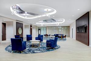 un vestíbulo con sillas azules, mesa y mesas en SpringHill Suites by Marriott Boston Logan Airport Revere Beach, en Revere