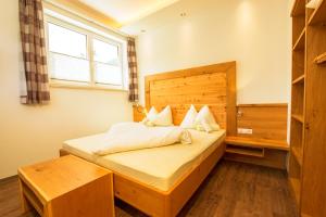 een slaapkamer met een bed met een houten hoofdeinde en een raam bij Apparthotel Panorama in Flachau