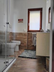 a bathroom with a toilet and a sink and a window at MANZONI APARTS - SUITE Superior in San Pellegrino Terme