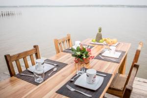 a wooden table with chairs and food on top of the water at Hotel Restaurant Chez Theo in Bopa