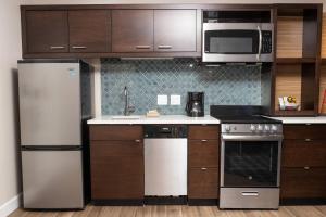 una cocina con electrodomésticos de acero inoxidable y armarios de madera en TownePlace Suites by Marriott Petawawa en Petawawa