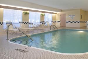 Una gran piscina en una habitación con sillas y mesas. en Fairfield Inn & Suites Mt. Pleasant, en Mount Pleasant