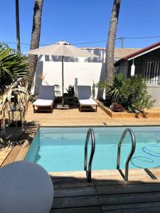 a swimming pool with two chairs and an umbrella at VILLA 'Le Refuge' Piscine chauffée 300 m plage in La Tranche-sur-Mer