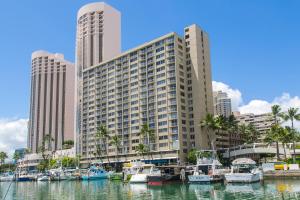 a group of boats docked in a marina with tall buildings at Ilikai Marina 985 in Honolulu