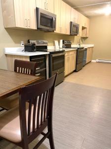 an empty kitchen with a table and a microwave at The George Dawson Inn & Conference Centre in Dawson Creek +38 photos