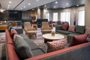 a waiting room with couches and chairs and a tv at Courtyard by Marriott Buffalo Airport in Cheektowaga