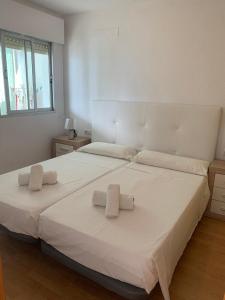 sypialnia z dużym białym łóżkiem z ręcznikami w obiekcie SERVICE APART LAZARO- Apartamentos Aguamarina 58 w mieście Calpe