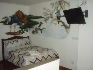 1 dormitorio con una pintura en la pared en Hostal Limoncocha en Tena