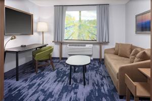 een woonkamer met een bank en een bureau in een hotelkamer bij Fairfield Inn & Suites by Marriott Indianapolis Greenfield in Greenfield