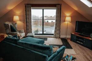 a living room with a couch and a television at The Sea Loft Castlerock. in Castlerock